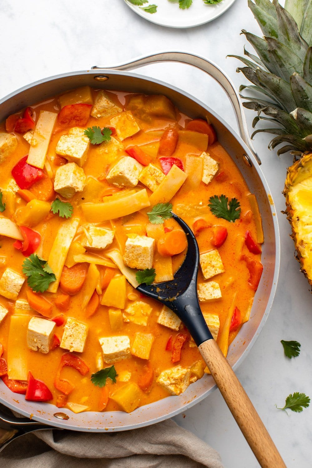 tofu pineapple curry in large sauté pan on marble background
