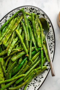 cooked green beans in speckled white serving tray