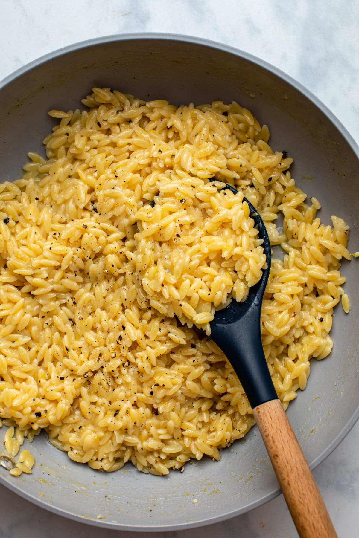 lemon pepper orzo in sauté pan with wooden spoon