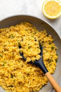 lemon pepper orzo in saute pan garnished with parsley and with lemon wedge on side