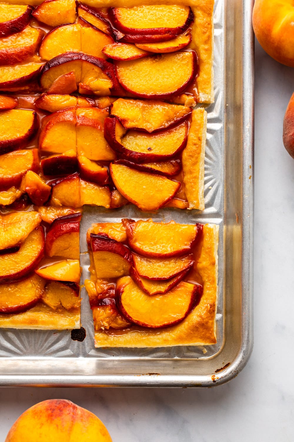 sliced puff pastry peach galette on baking sheet
