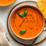 bowl of roasted tomato soup topped with olive oil and basil