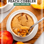 peach cobbler baked in small white ramekin on small wooden cutting board