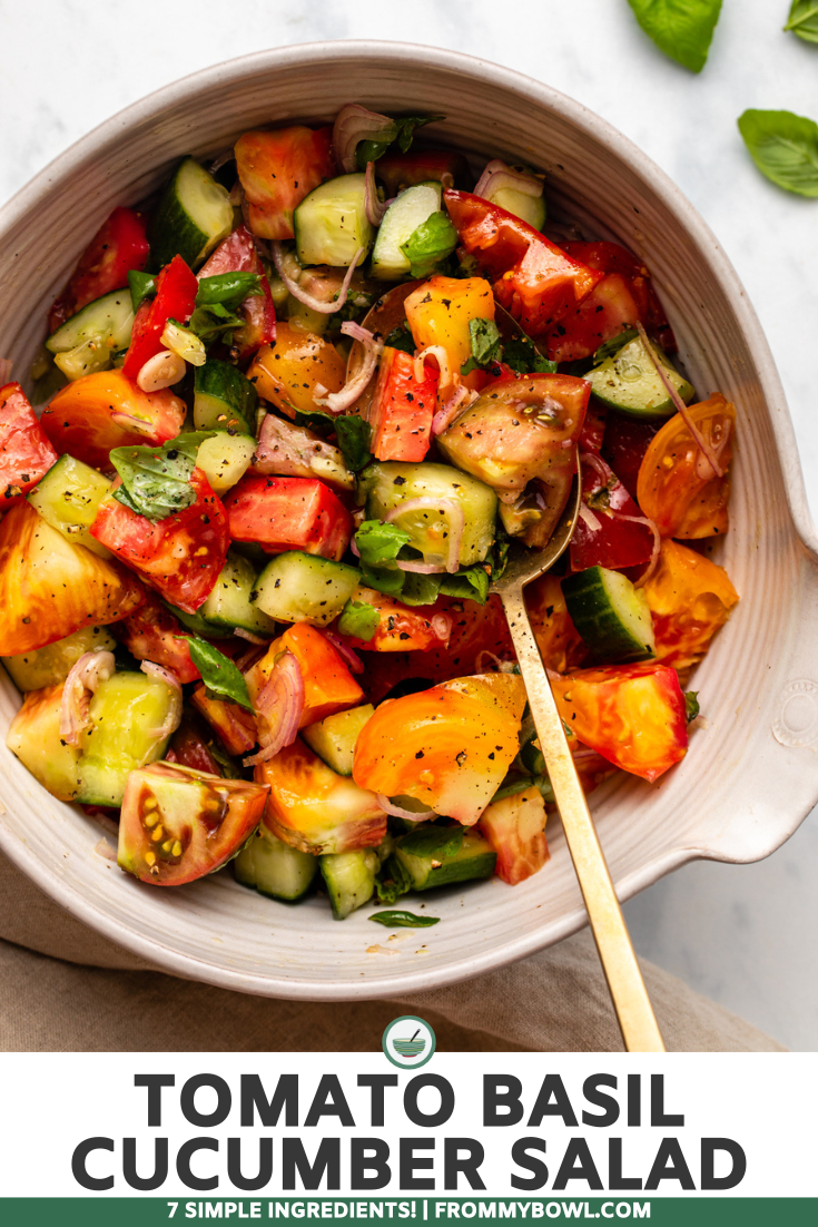 Tomato cucumber salad with basil and black pepper in ceramic bowl on marble countertop