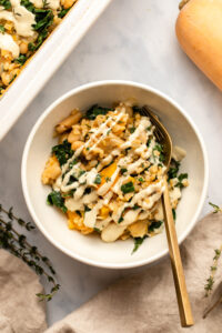 butternut squash casserole in bowl topped with cashew cream