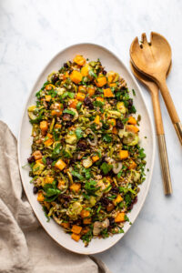 fall farro salad in serving dish with wooden tongs