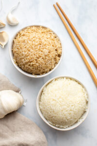 a bowl of white rice and a bowl of brown rice on a marble background
