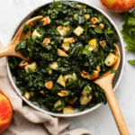 kale apple walnut salad in serving bowl with wooden salad spoons