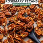Spatula scooping roasted pecans off baking sheet
