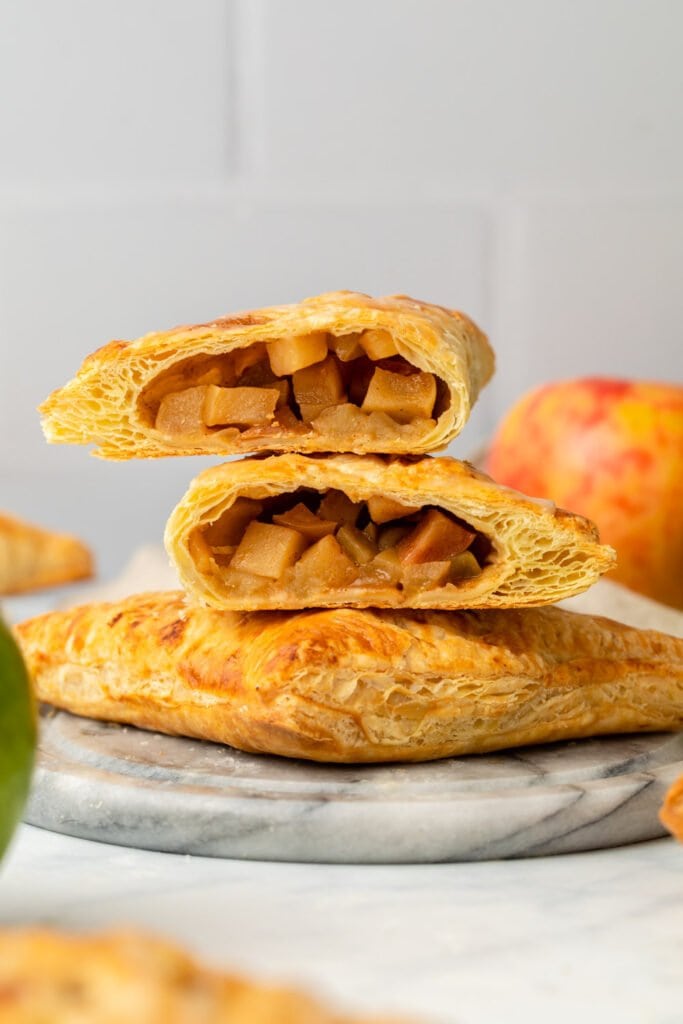 stack of cooked apple turnovers with top one cut in half to show texture
