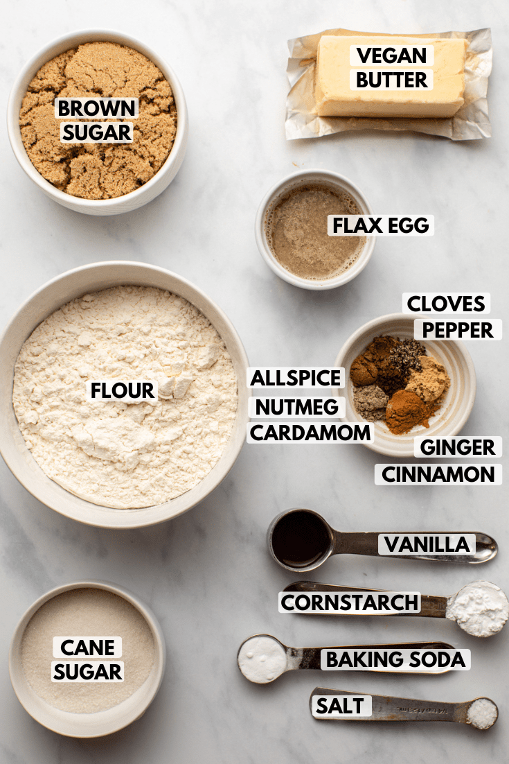 ingredients for chai sugar cookies in small bowls on marble countertop