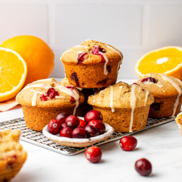 stack of cranberry orange muffins topped with orange glaze