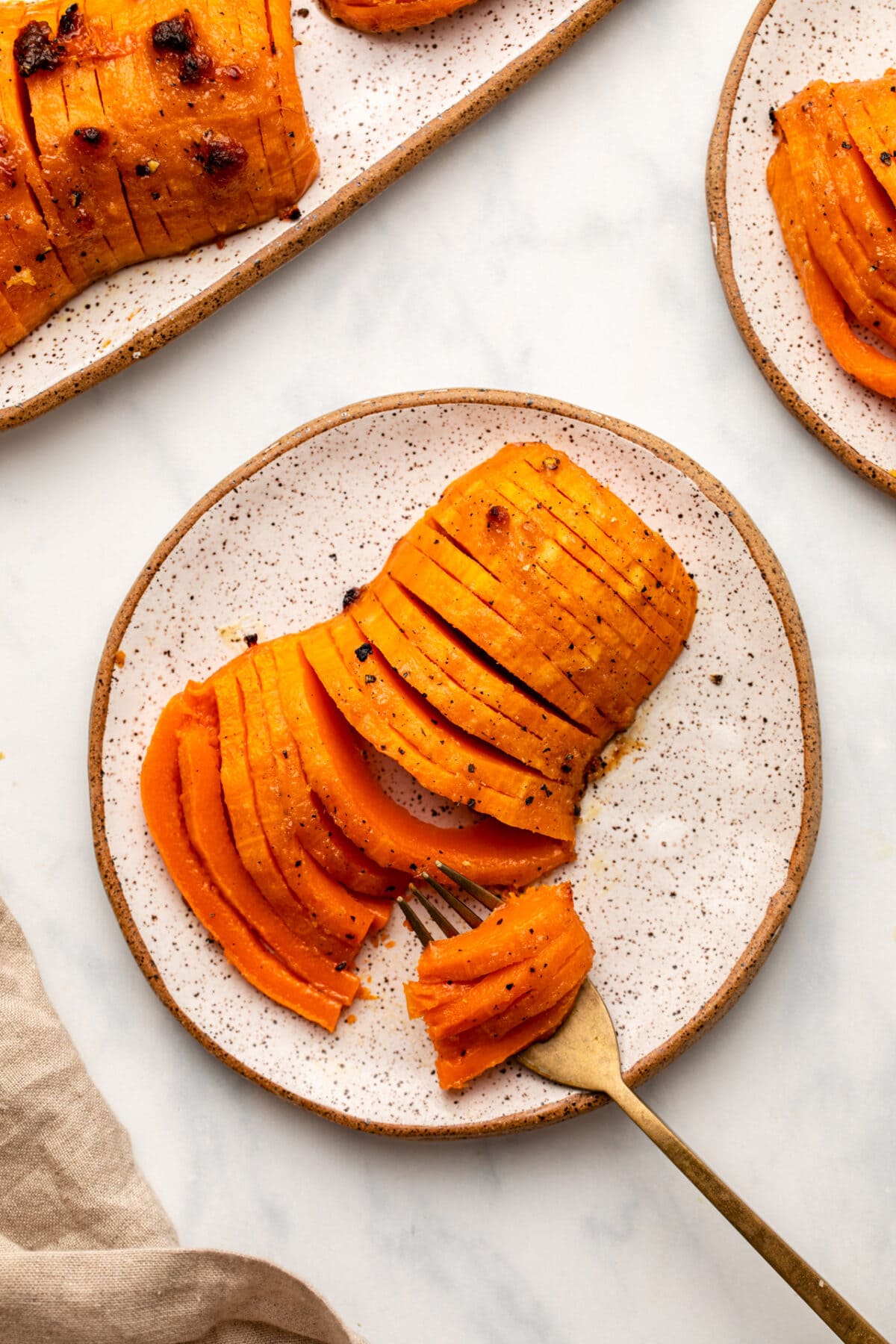 A fork slicing through roasted honeynut squash on small white plate