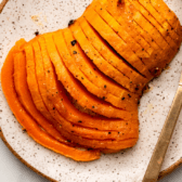 roasted honeynut squash on white serving plate topped with black pepper