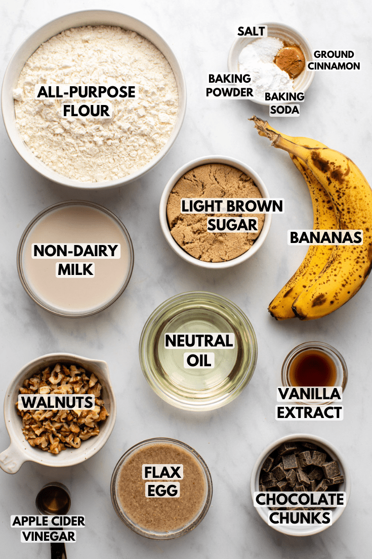 ingredients for banana muffins served in white bowls and laid out on a marble countertop