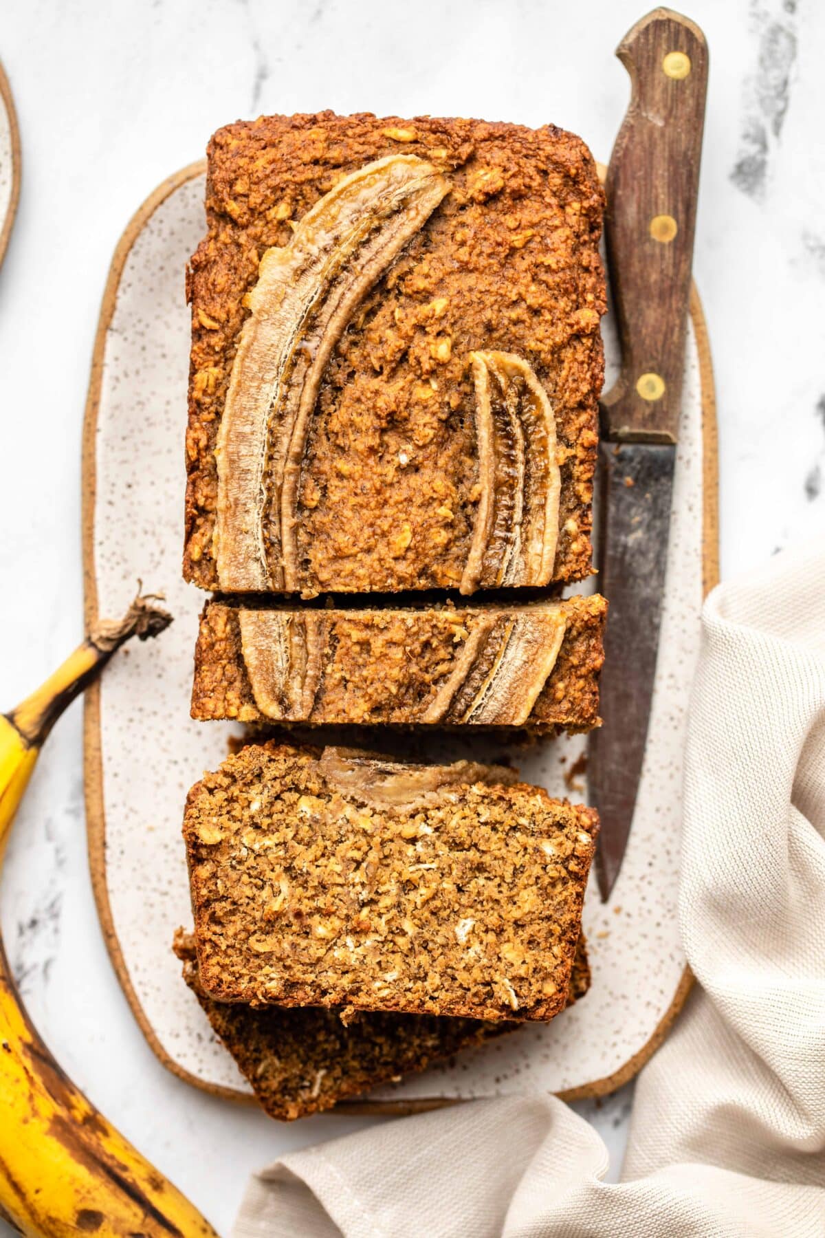 vegan banana bread served on a plate with three slices stacked on top of each other