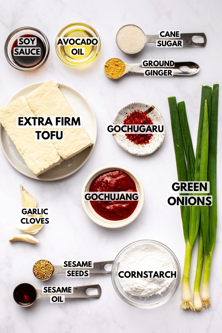 ingredients for saucy gochujang tofu laid out on a marble kitchen countertop served in various bowls