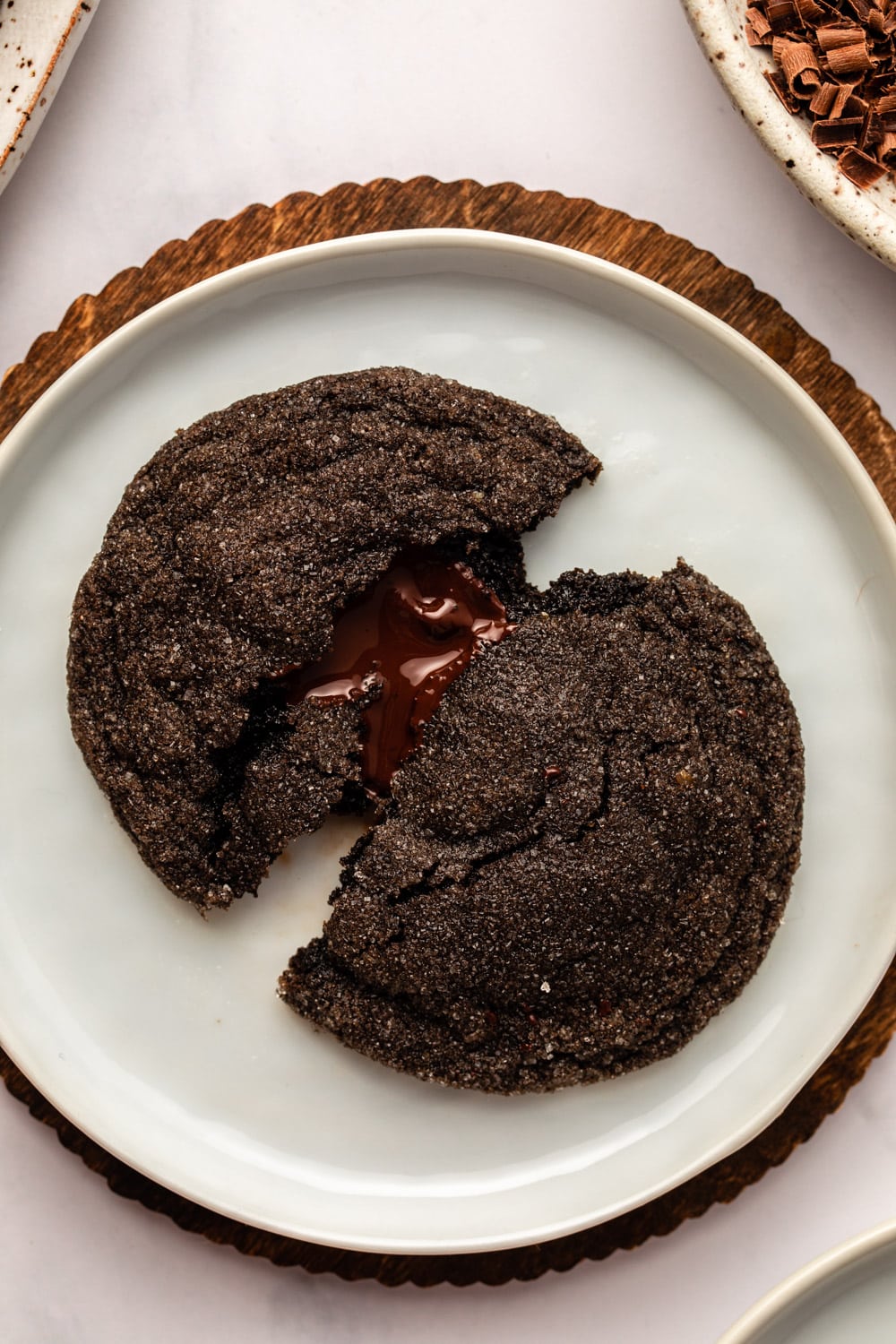 vegan chocolate cookie divided in half and served in a white plate with the chocolate filling melting on the plate