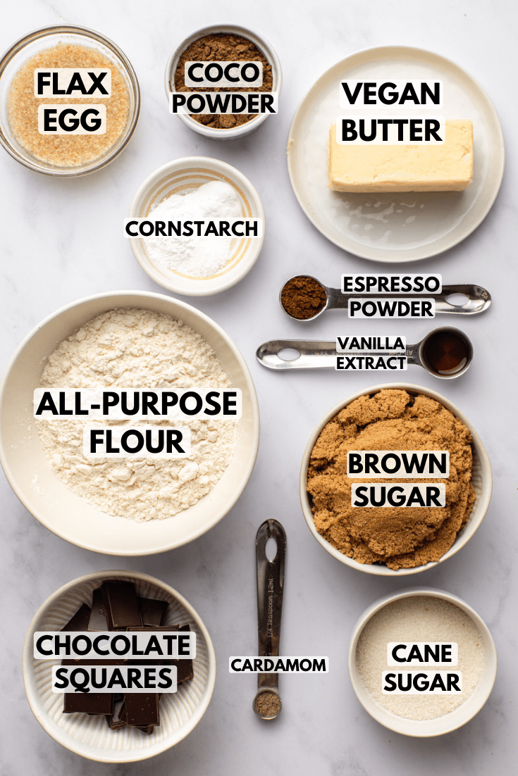 ingredients for vegan chocolate cookies laid on a marble kitchen countertop and served in various white bowls