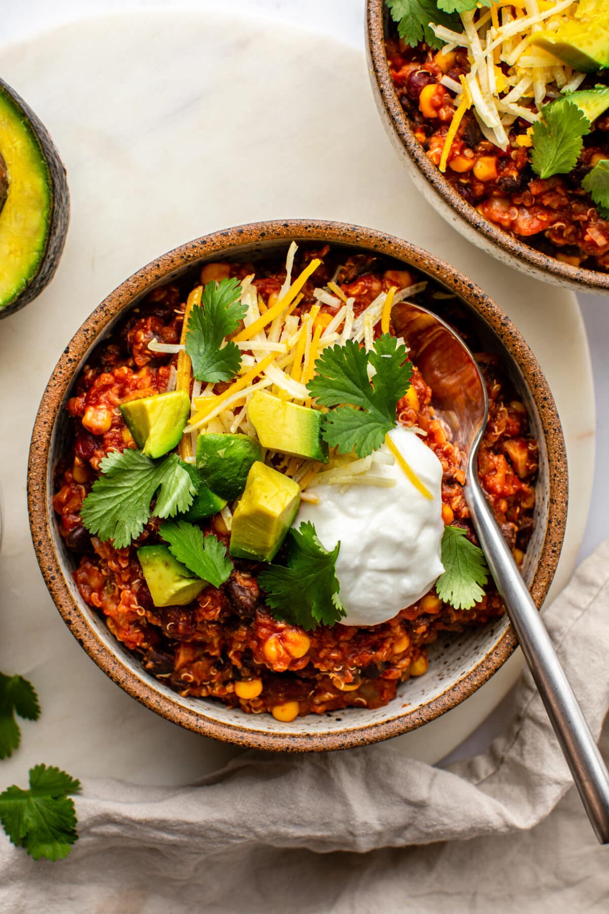 bean quinoa chili served in a bowl and topped with avocado, cilantro and sour cream