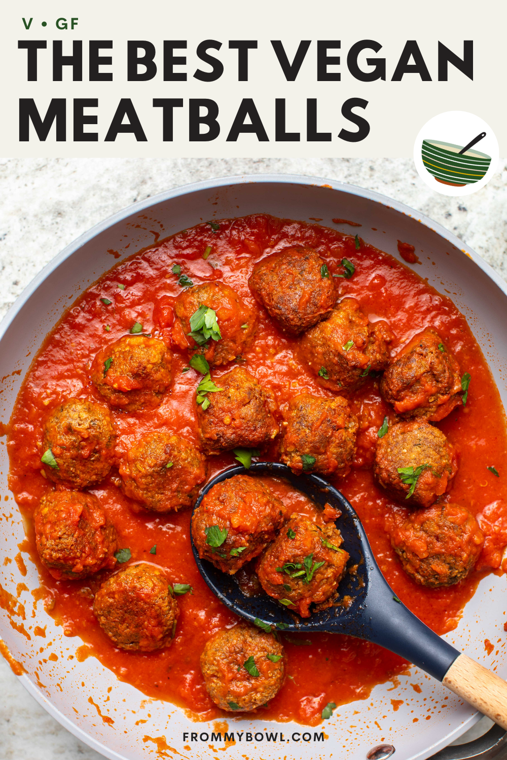vegan meatballs with tomato sauce in a pan with a serving spoon scooping up two meatballs