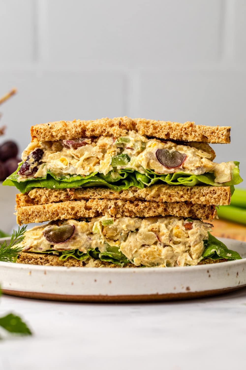vegan chickpea salad sandwich sliced in half and stacked on white plate
