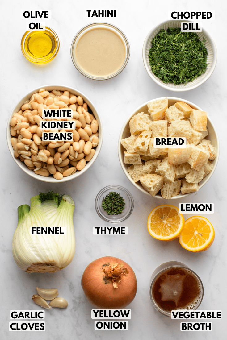 ingredients for the creamy white bean soup laid out on a marble kitchen countertop in various sizes of white bowls