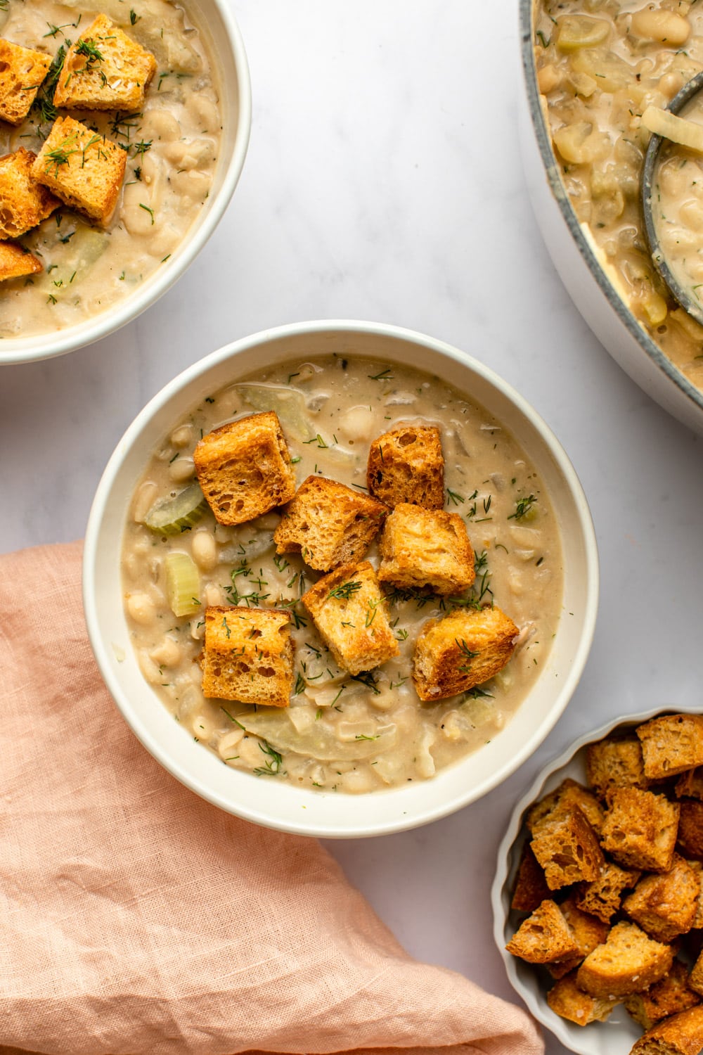 creamy white bean soup served in a white bowl and topped with croutons