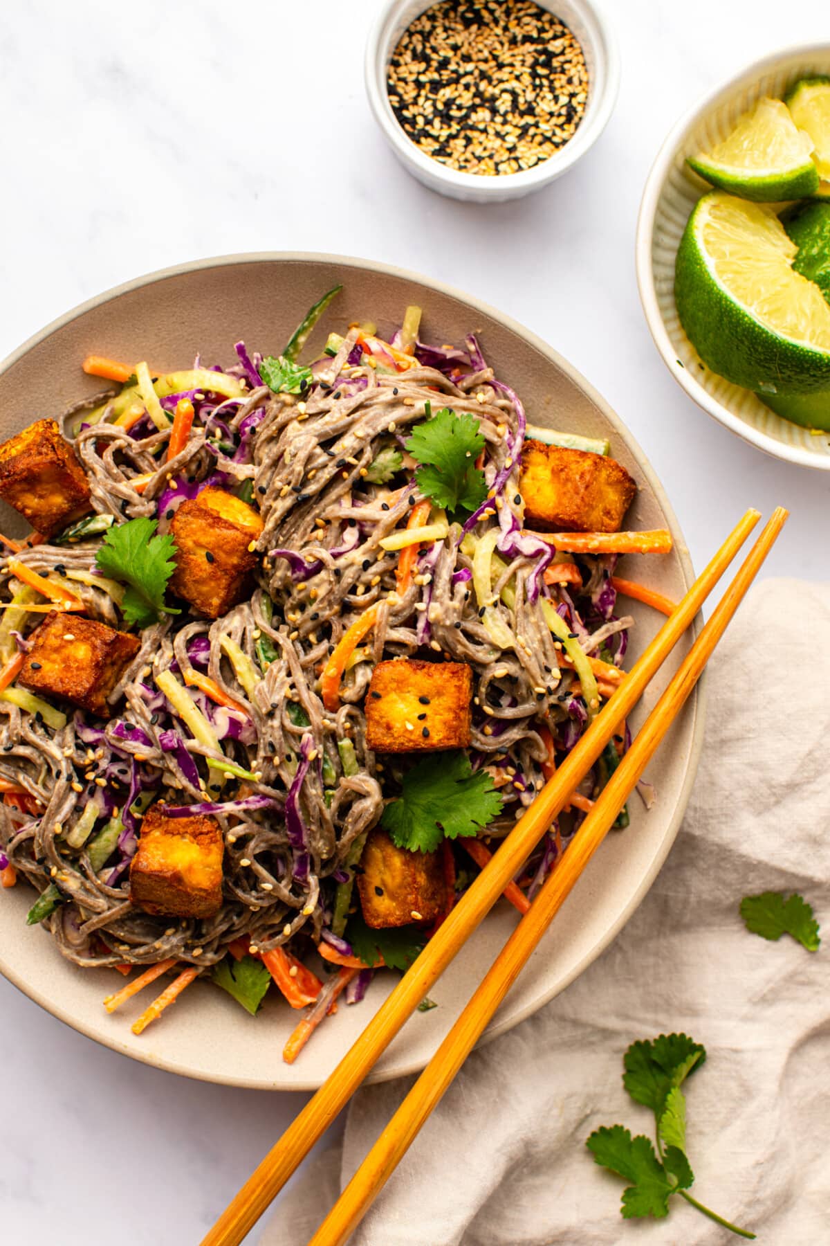 soba noodle salad served in a white bowl topped with crispy tofu 