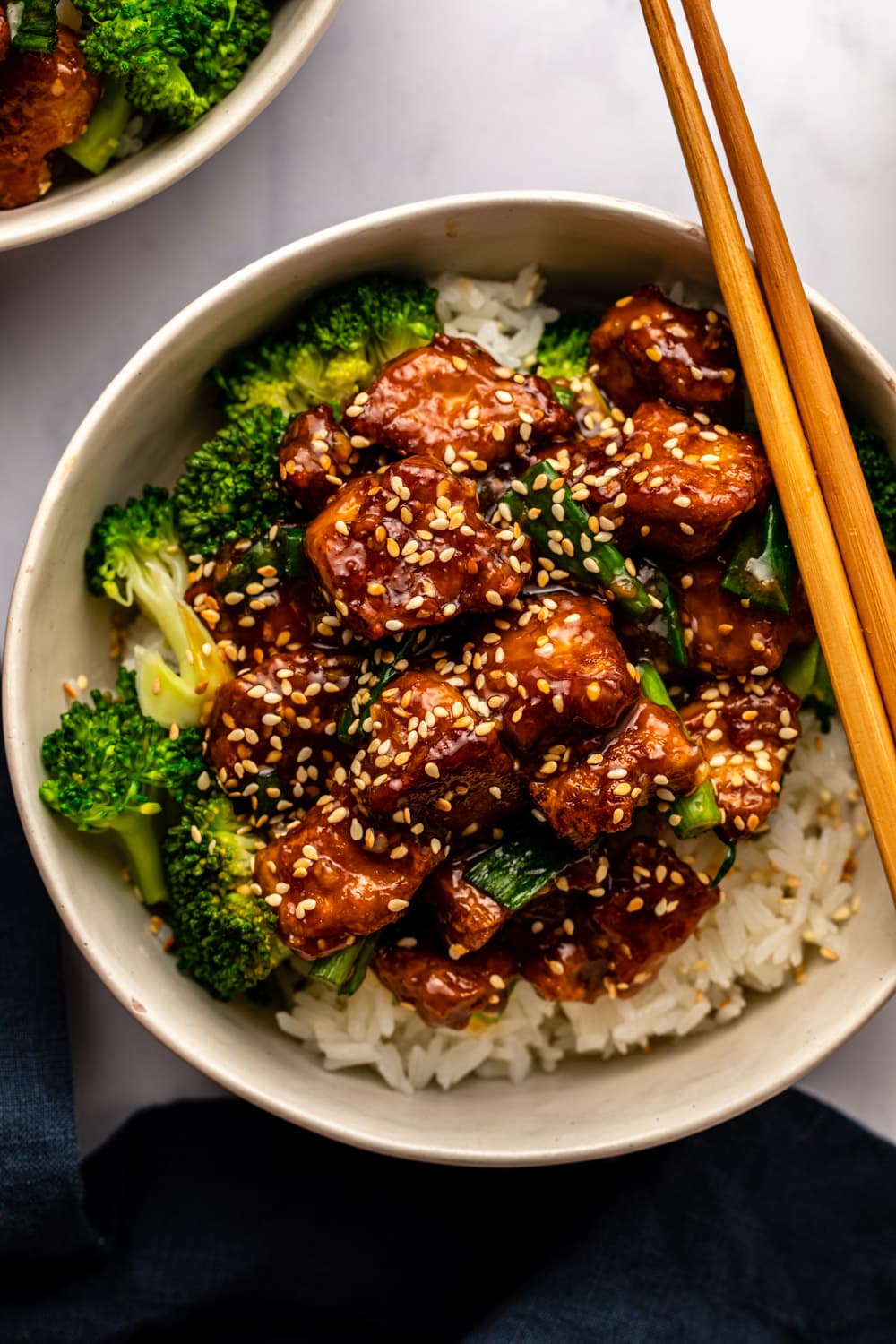 teriyaki tofu served over rice with veggies in a white bowl