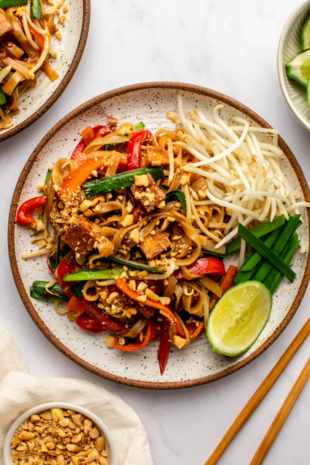 vegan pad thai served on a plate topped with lime and peanuts