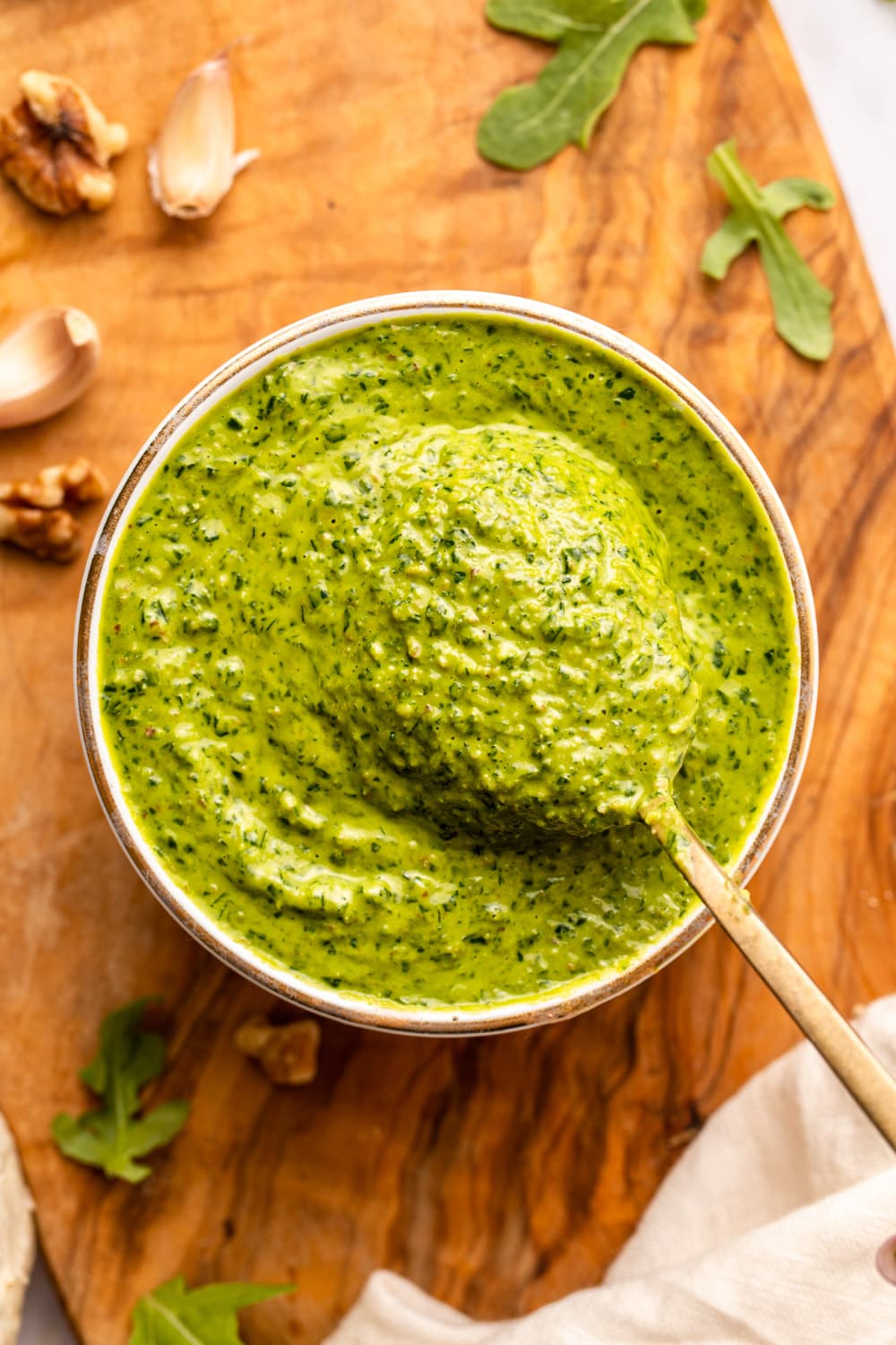 arugula pesto served in a cup with a spoon scooping up a portion