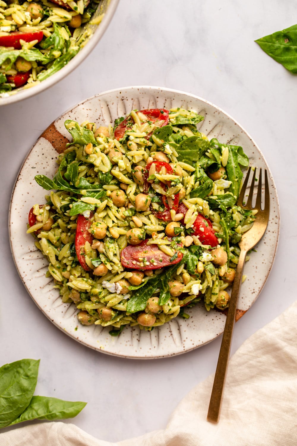 pesto orzo salad served on a plate with a work on the side