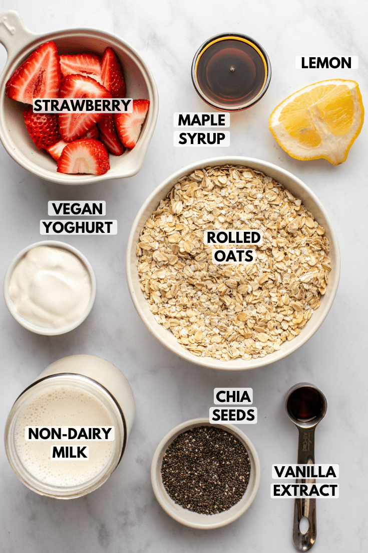 ingredients for strawberry overnight oats laid out on a marble kitchen countertop