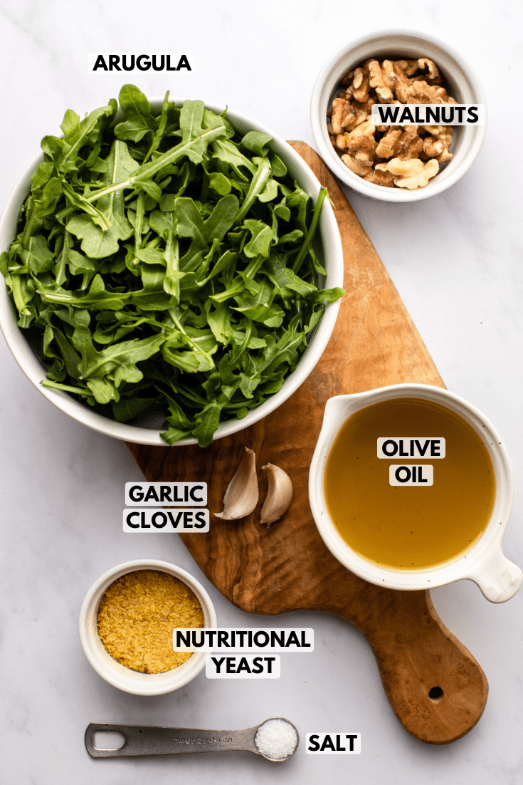 ingredients for arugula pesto laid out on a cutting board