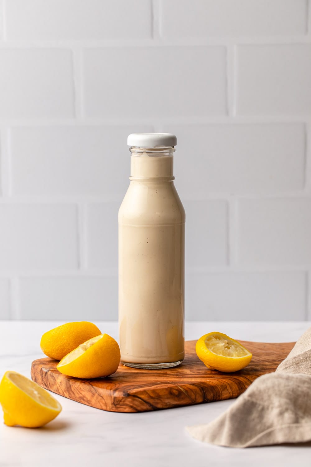 tahini dressing stored in a bottle with lemons laid around as decoration
