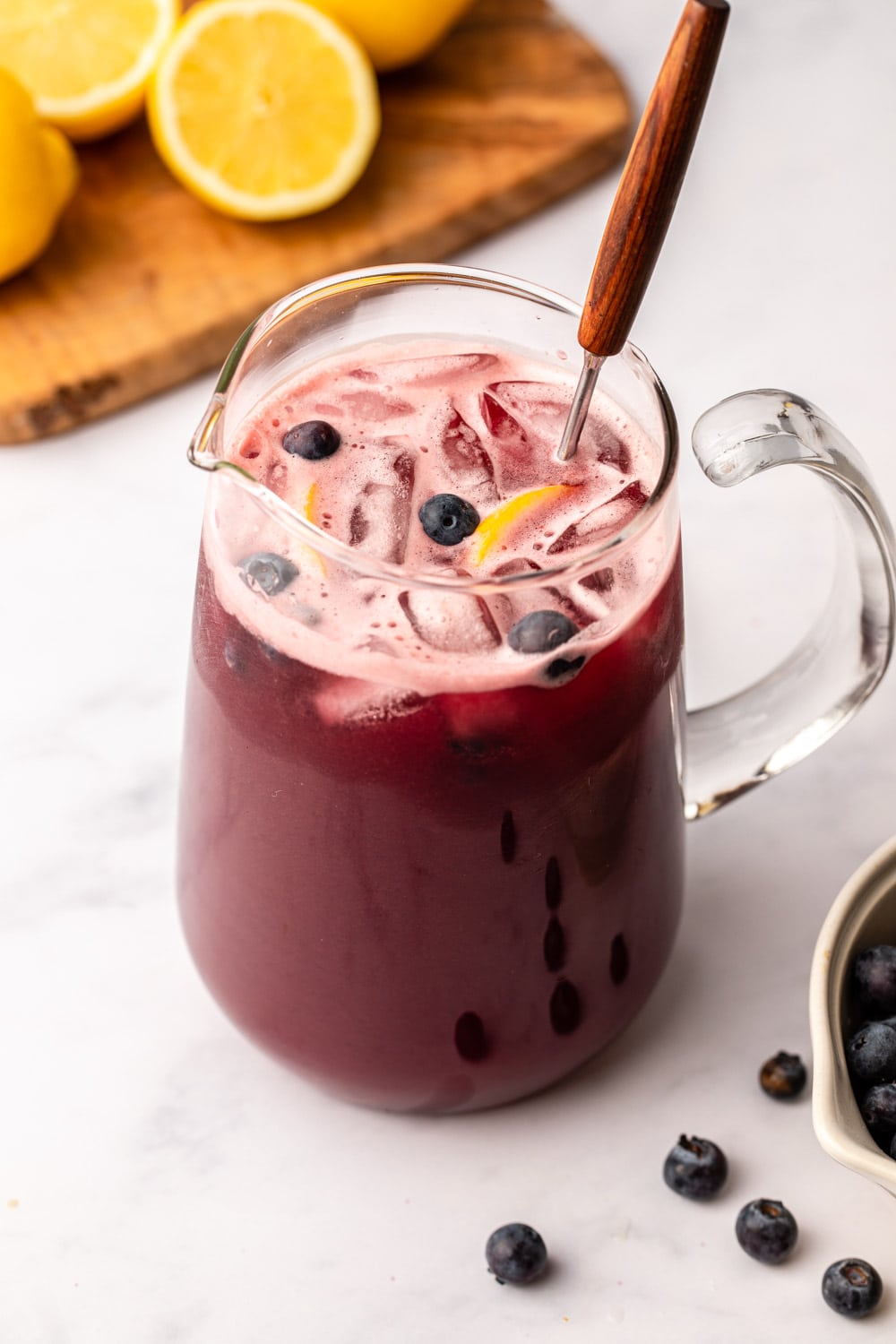 blueberry lemonade served in a big glass topped with blueberries and sliced lemons