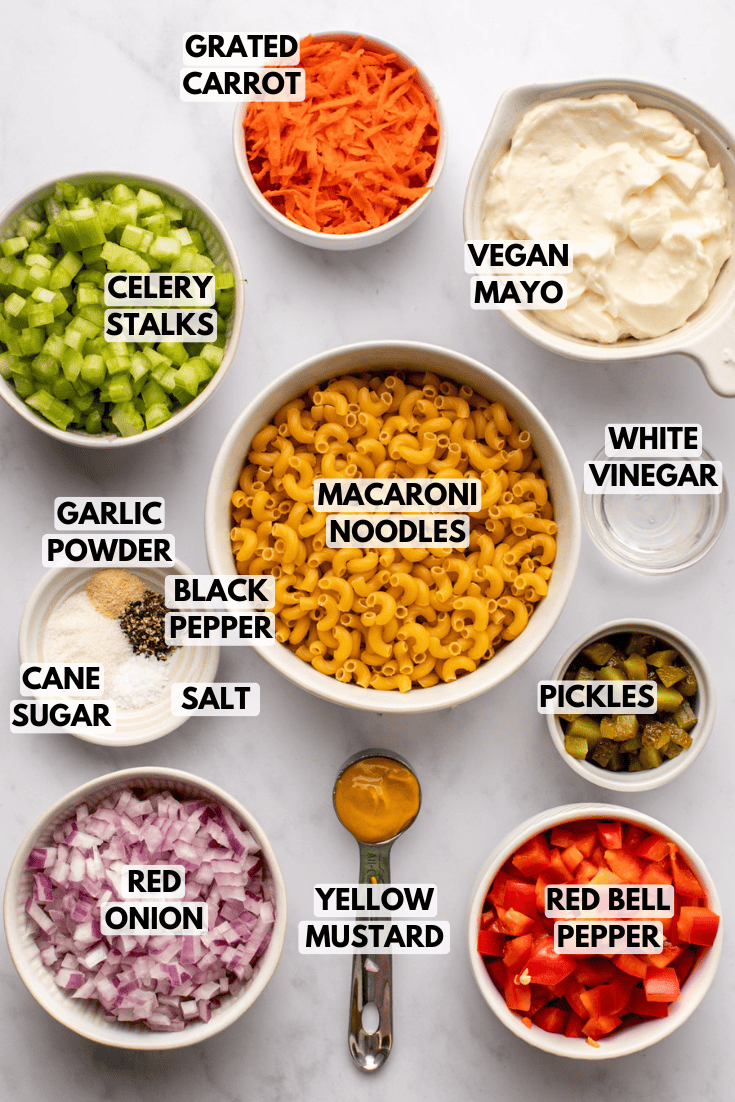 ingredients for vegan macaroni salad laid out on a marble kitchen countertop