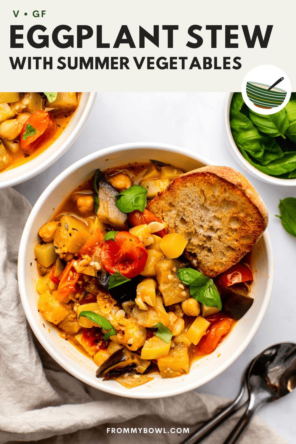 eggplant stew served in a white bowl topped with fresh basil leaves and toasted bread