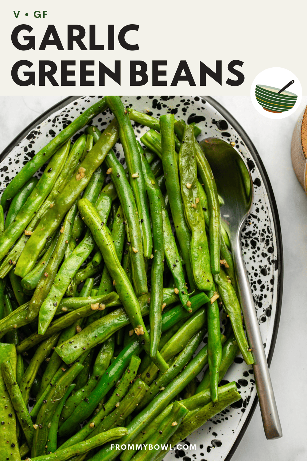 garlic green beans served on a wide speckled serving tray with a spoon on the side