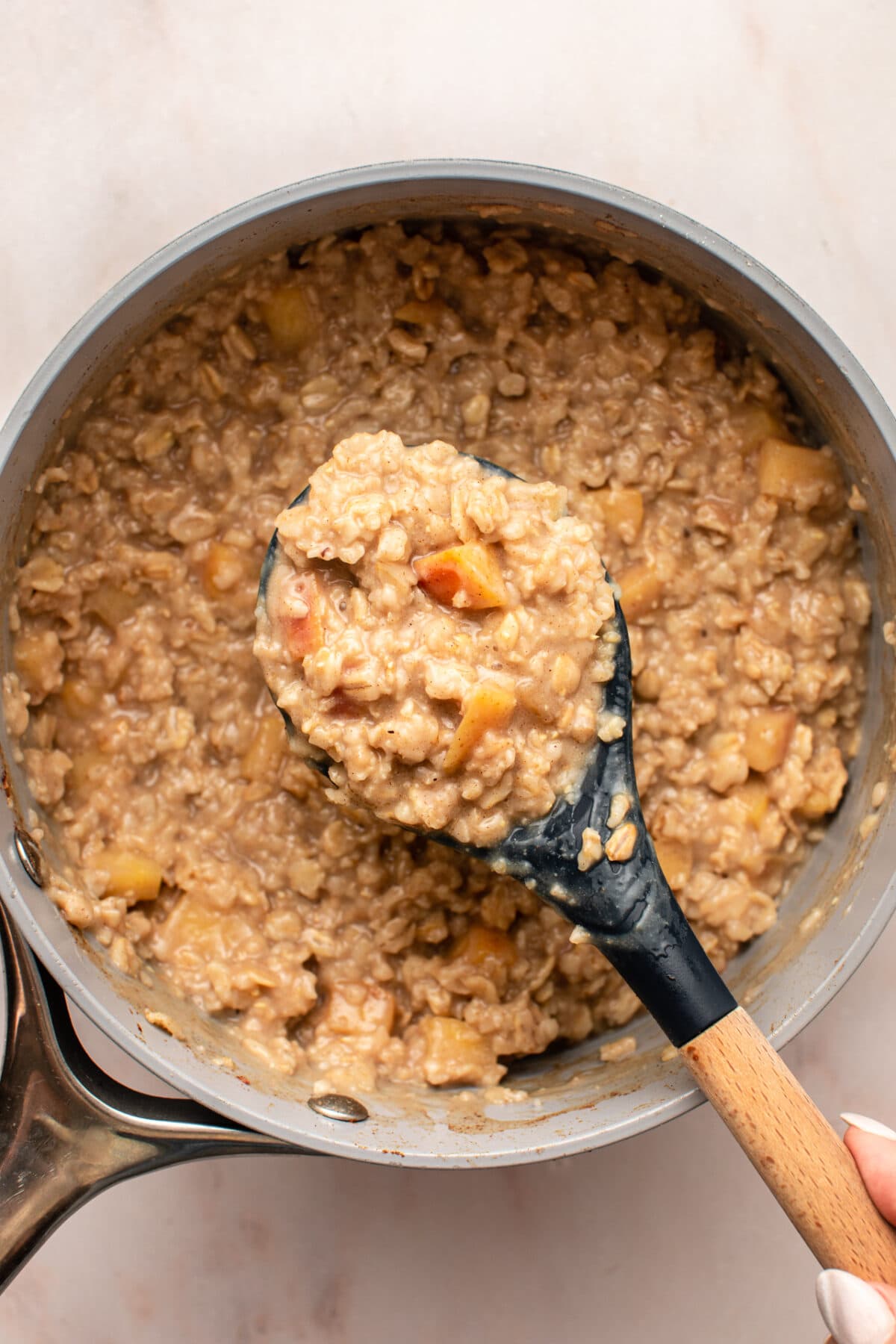 a zoomed in image on the cooked down version of the oatmeal with a serving spoon scooping up a big portion to show its texture