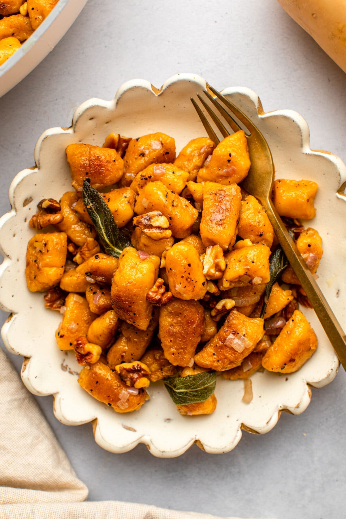butternut squash gnocchi served on a flower shaped white plate with a fork ready to dig in