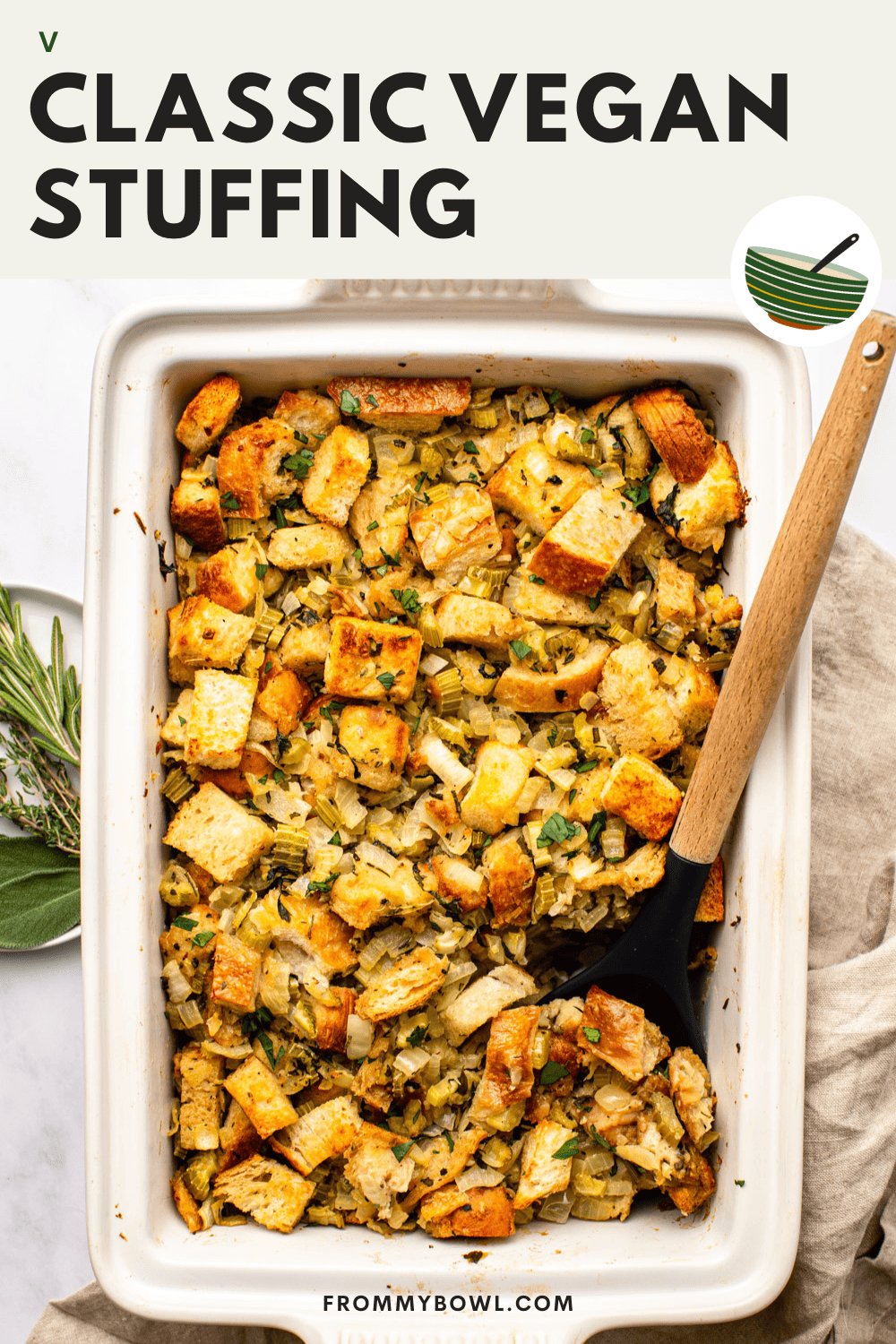vegan stuffing freshly out of the oven in a white baking dish with a serving spoon dug in