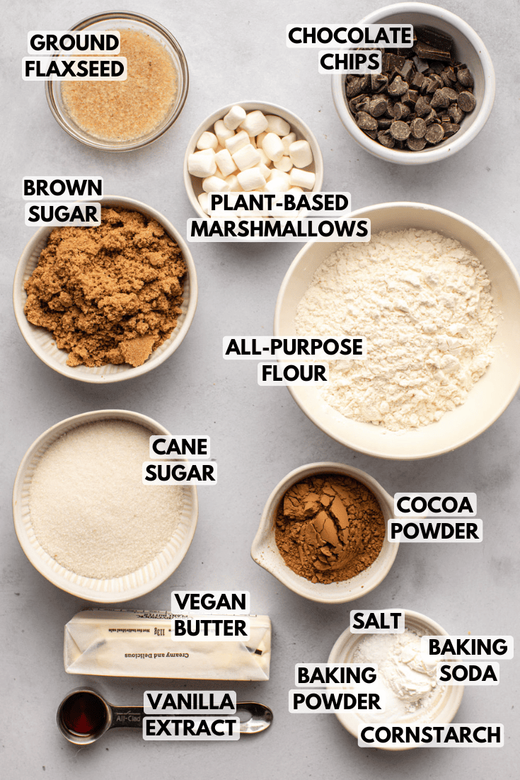 ingredients for hot cocoa cookies in various sizes of white bowls laid out on a marble kitchen countertop
