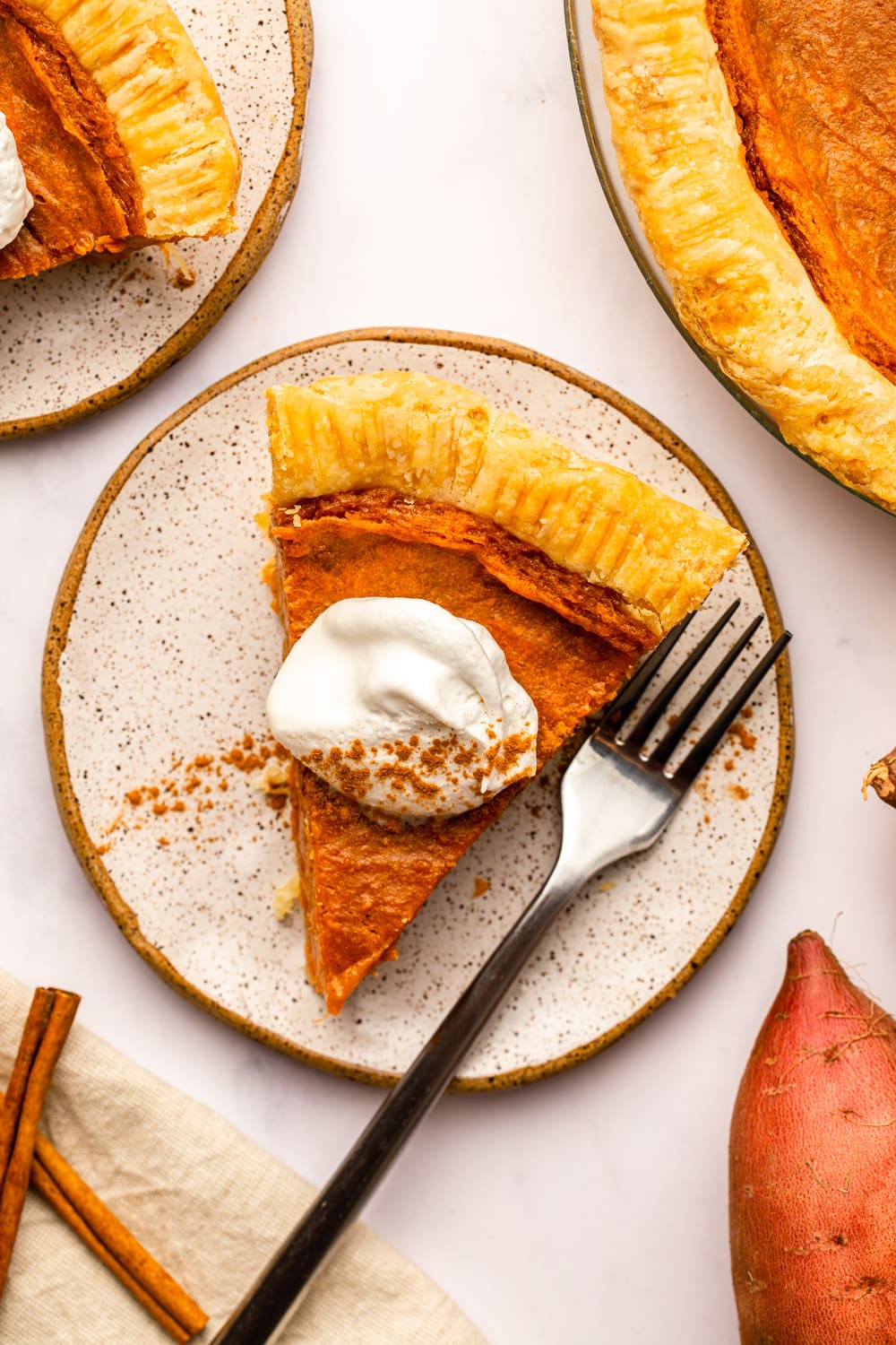 a slice of vegan sweet potato pie served on a white plate topped with coconut cream
