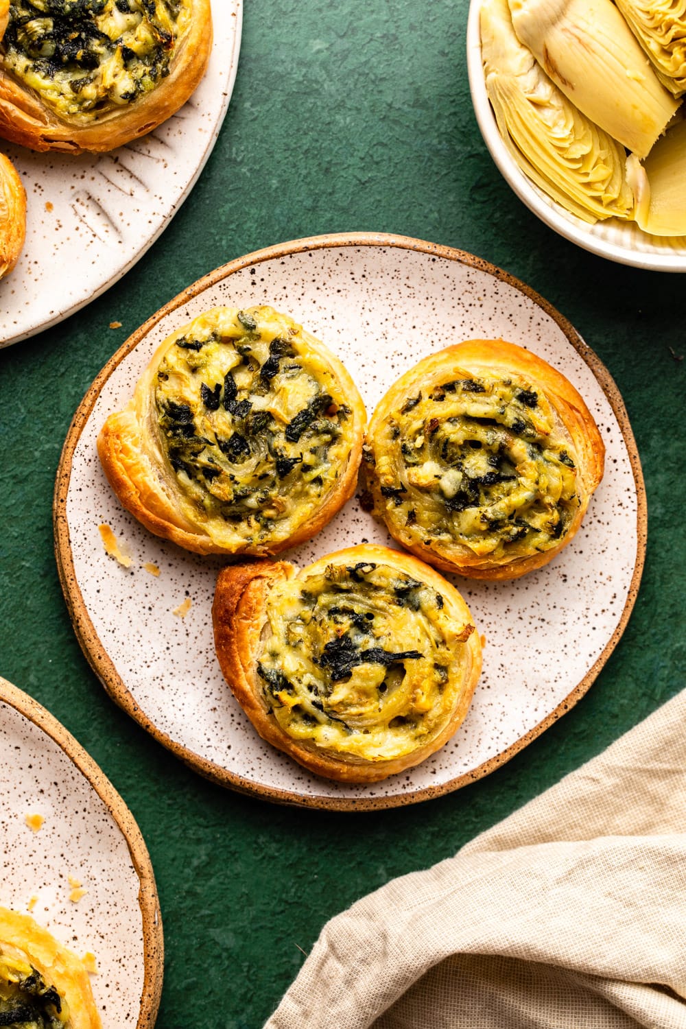 three spinach artichoke pinwheels served on a white plate