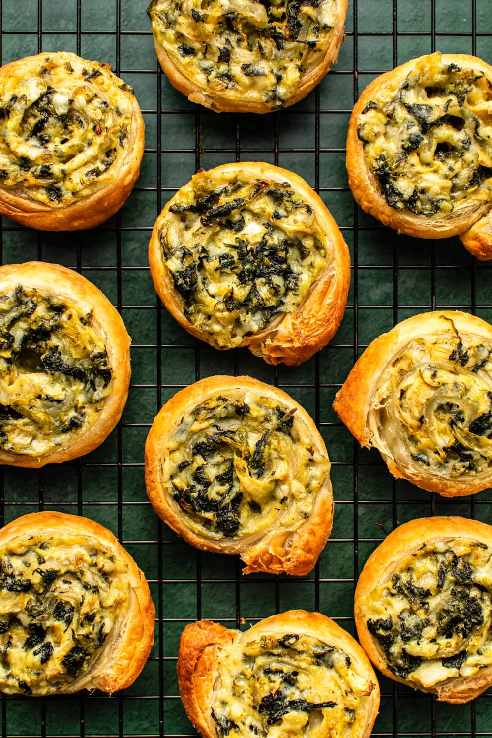 spinach artichoke pinwheels laid out on a cooling rack