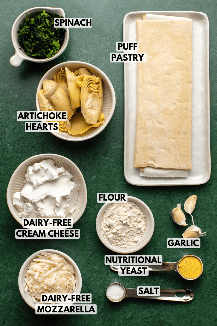 ingredients for spinach artichoke puff pastry laid out on a dark green kitchen countertop