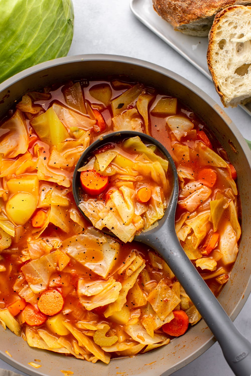 a zoomed in image of the hearty cabbage soup with a serving spoon scooping up a portion