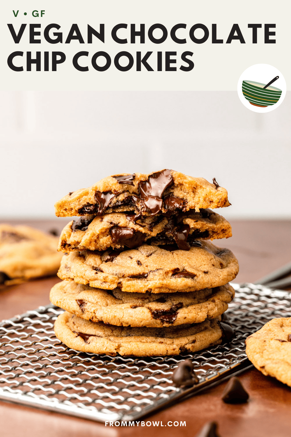 four chocolate chip cookies stacked on top with the cookie on top divided into two to showcase its texture and the melting chocolate chips